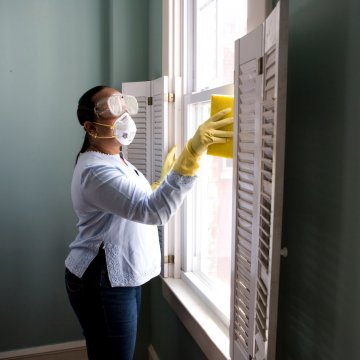 cleaning the inside of a house with a mask on